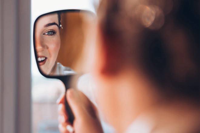 Bride admiring her makeup in a hand mirror